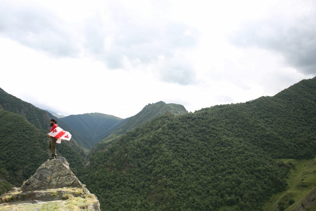 Brodaty mężczyzna z flagą gruziską w górach kaukazu, Chewsuretia, Gruzja