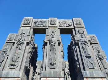 Trzy masywne kolumny z rzeźbami tworzące bramę do monumentu Kronika Gruzji