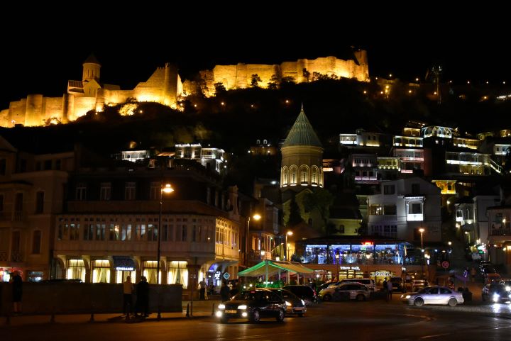 Stare miasto Tbilisi z cerkwią i oświetloną twierdzą Narikala na górze.
