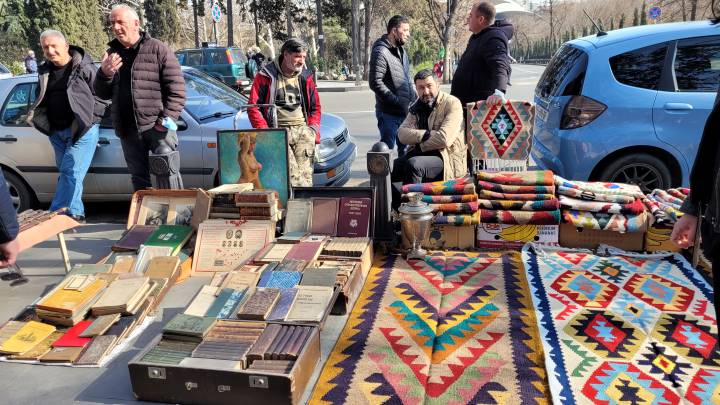 Targ z kolorowymi dywanami i starymi książkami na ulicy z sześcioma mężczyznami w Tbilisi, Suchy Most, Gruzja