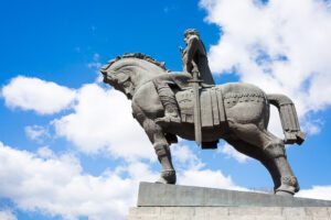 Pomnik kamienny założyciela Tbilisi króla Wachtanga Gorgasaliego na koniu z mieczem na boku konia i w pozie błogosławiącej.