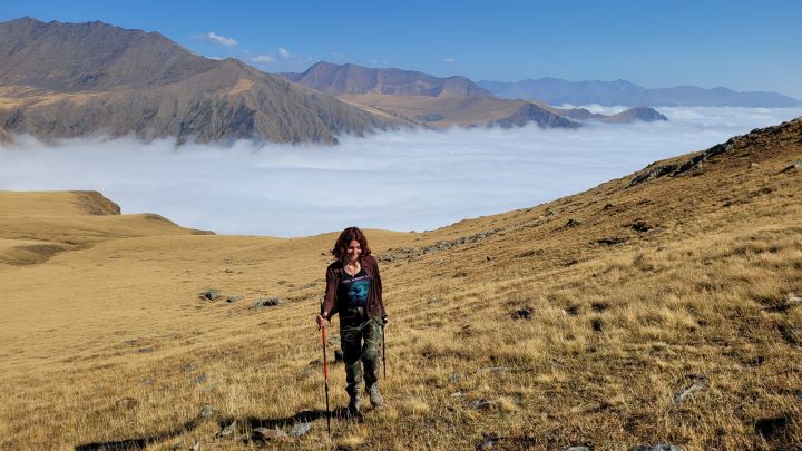 Dziewczyna z kijkami trekkingowymi w górach ponad chmurami, Gruzja