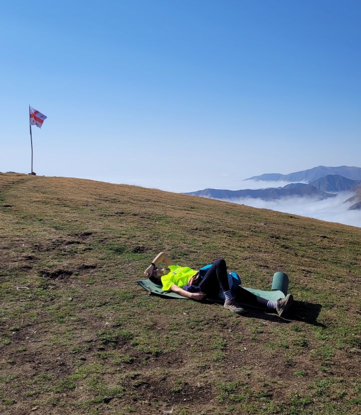 Dziewczyna leży na trawie na tle gruzińskiej flagi i góry, Gruzja